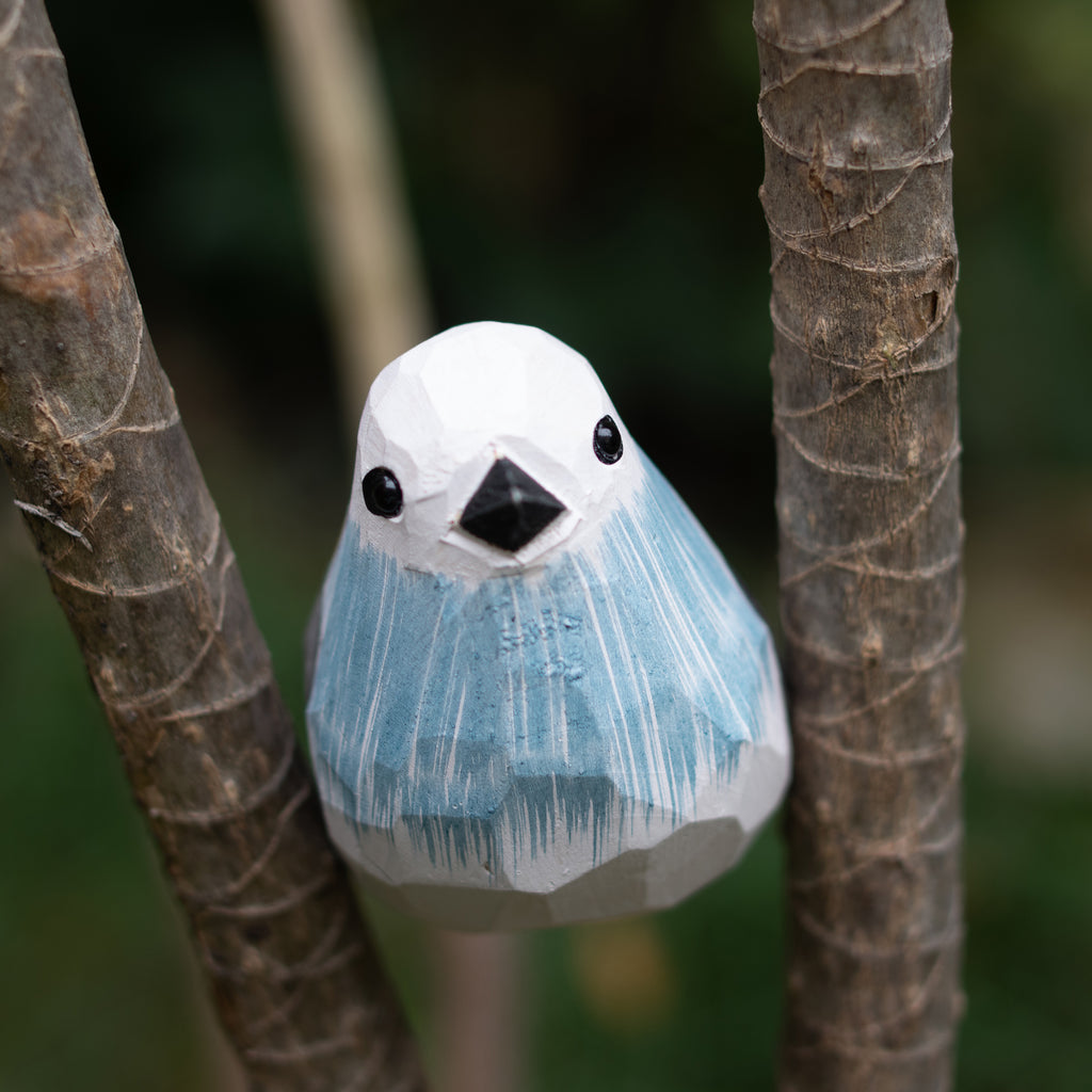 Hand-carved wooden figurine of a long-tailed tit perched on a branch