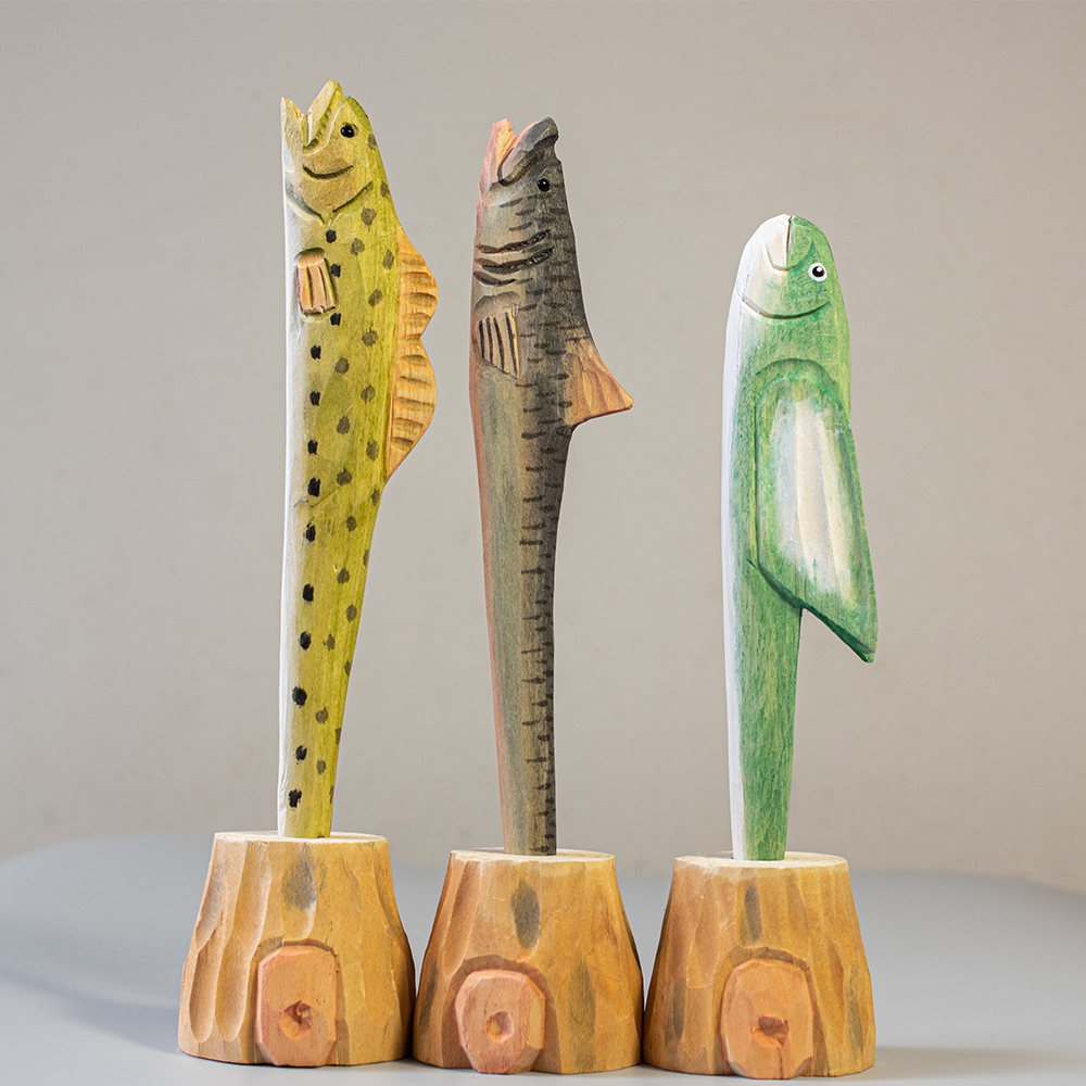 Three wooden pen shaped like animals on stands against a plain background