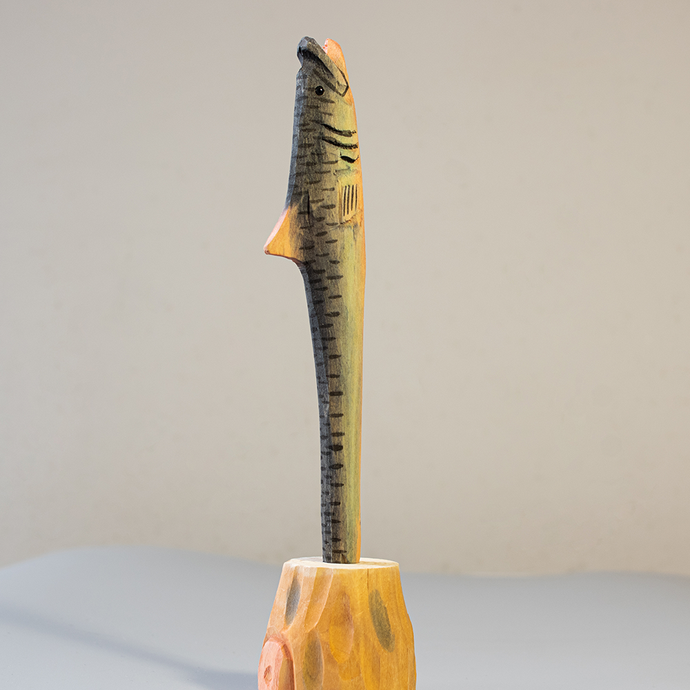 Handcrafted wooden bass-shaped pen on a plain background