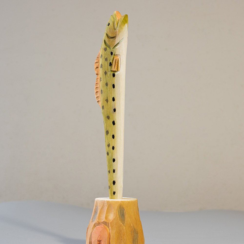 Wooden pen with fish design on a gray background