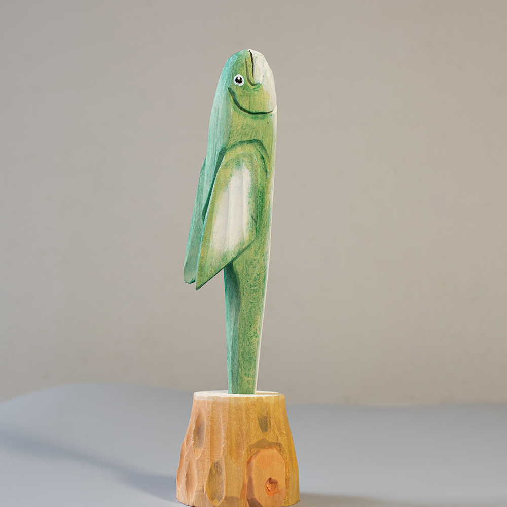 Wooden fish figurine on a wooden base against a plain background