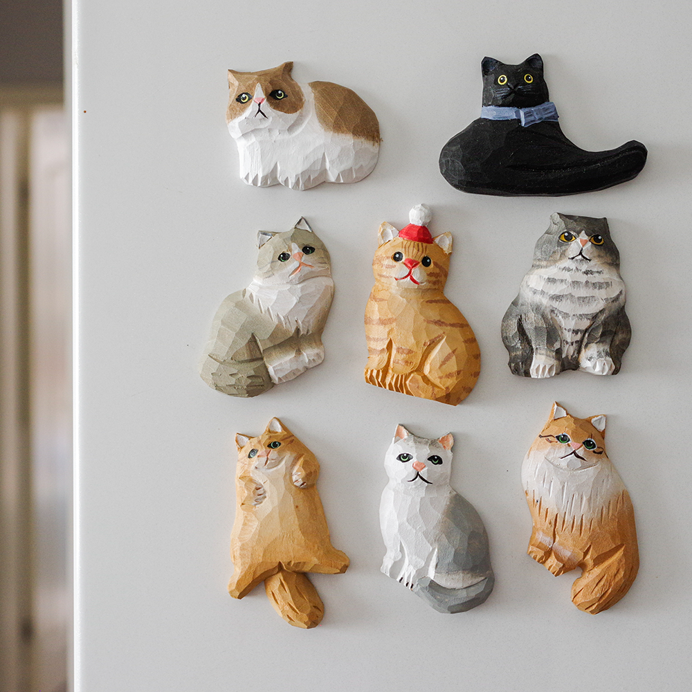 Set of cat-shaped decorative magnets on a fridge