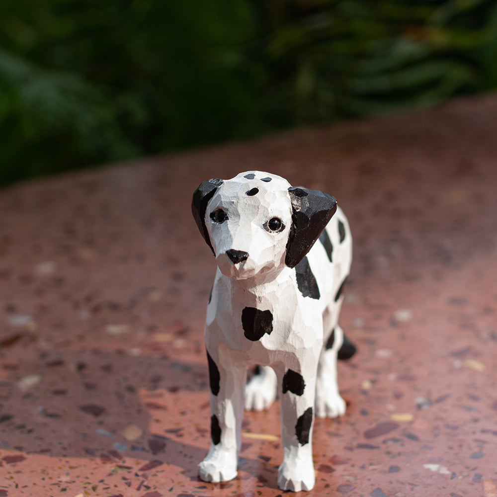 A hand-carved basswood figurine of a Dalmatian dog with a happy expression, featuring black spots and a white coat.