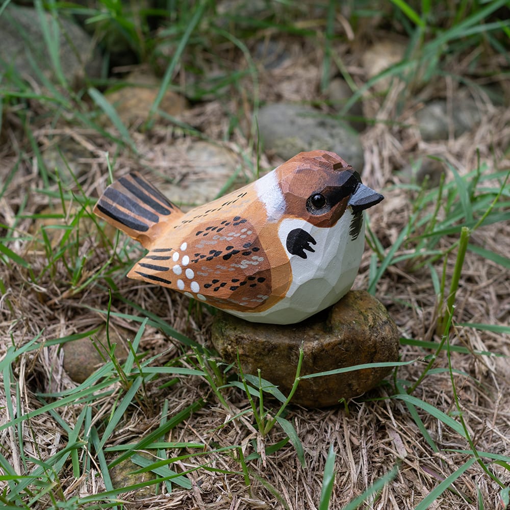 Wooden Eurasian Tree Sparrow figurine on a rock in a natural setting