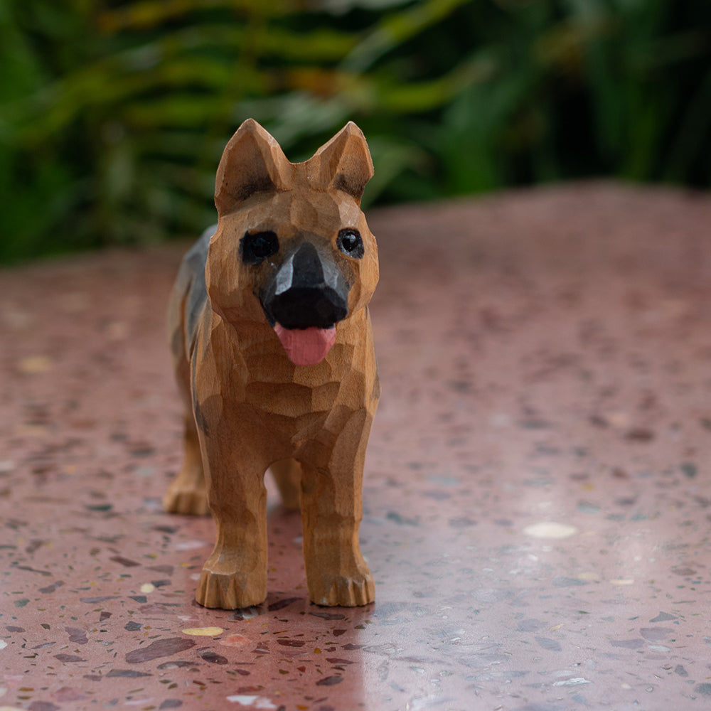 A hand carved wooden figurine of a German Shepherd.