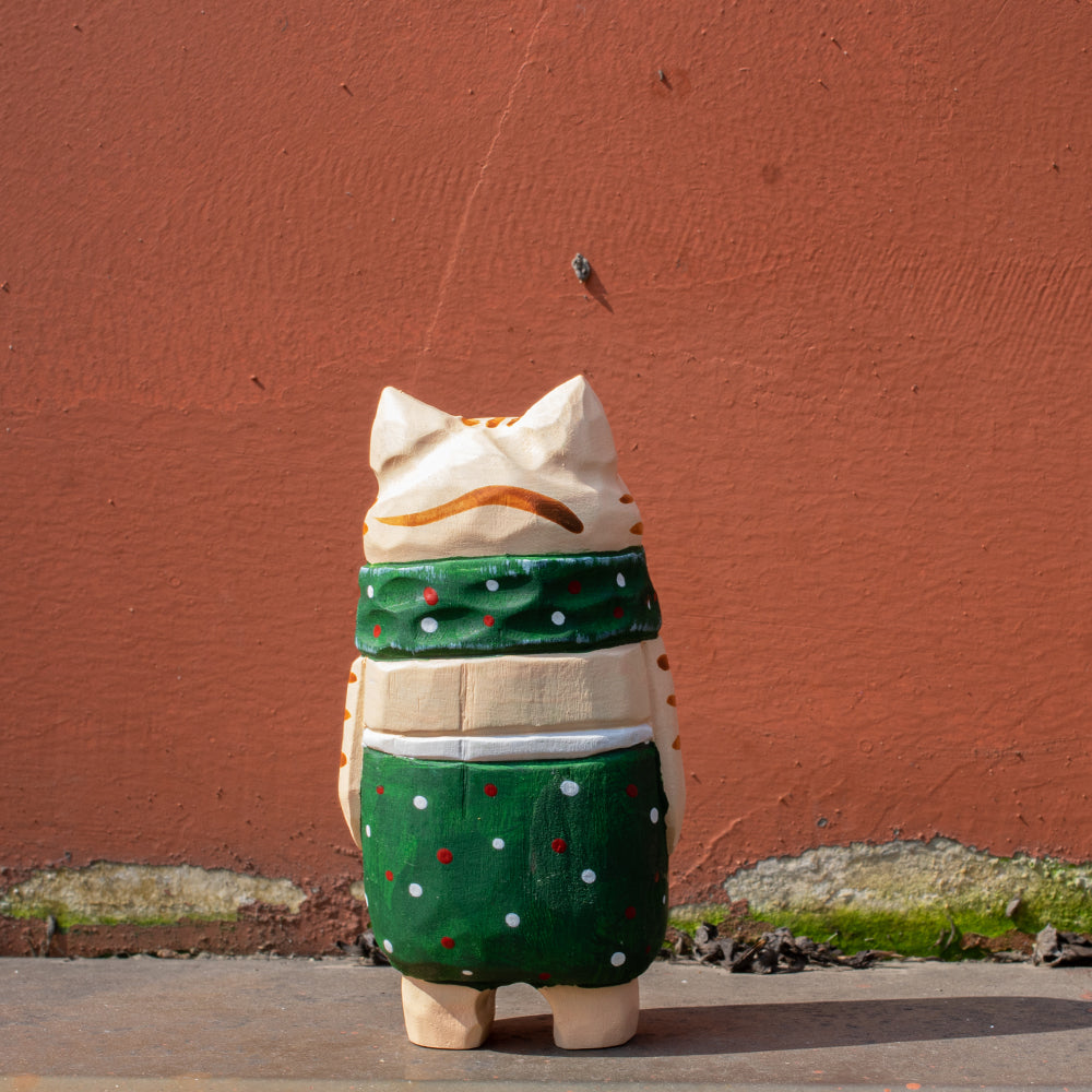 Hand-carved wood figurine of a festive green elf cat. Unique carved wood figure, traditional wood art, detailed wooden figurine, and high-quality wood carving.