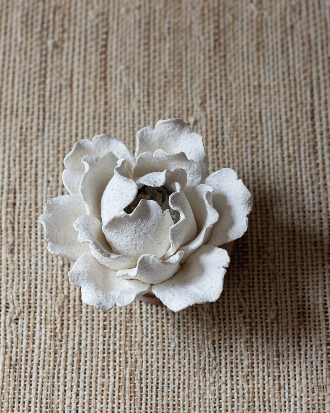 White ceramic incense holder on a linen mat.