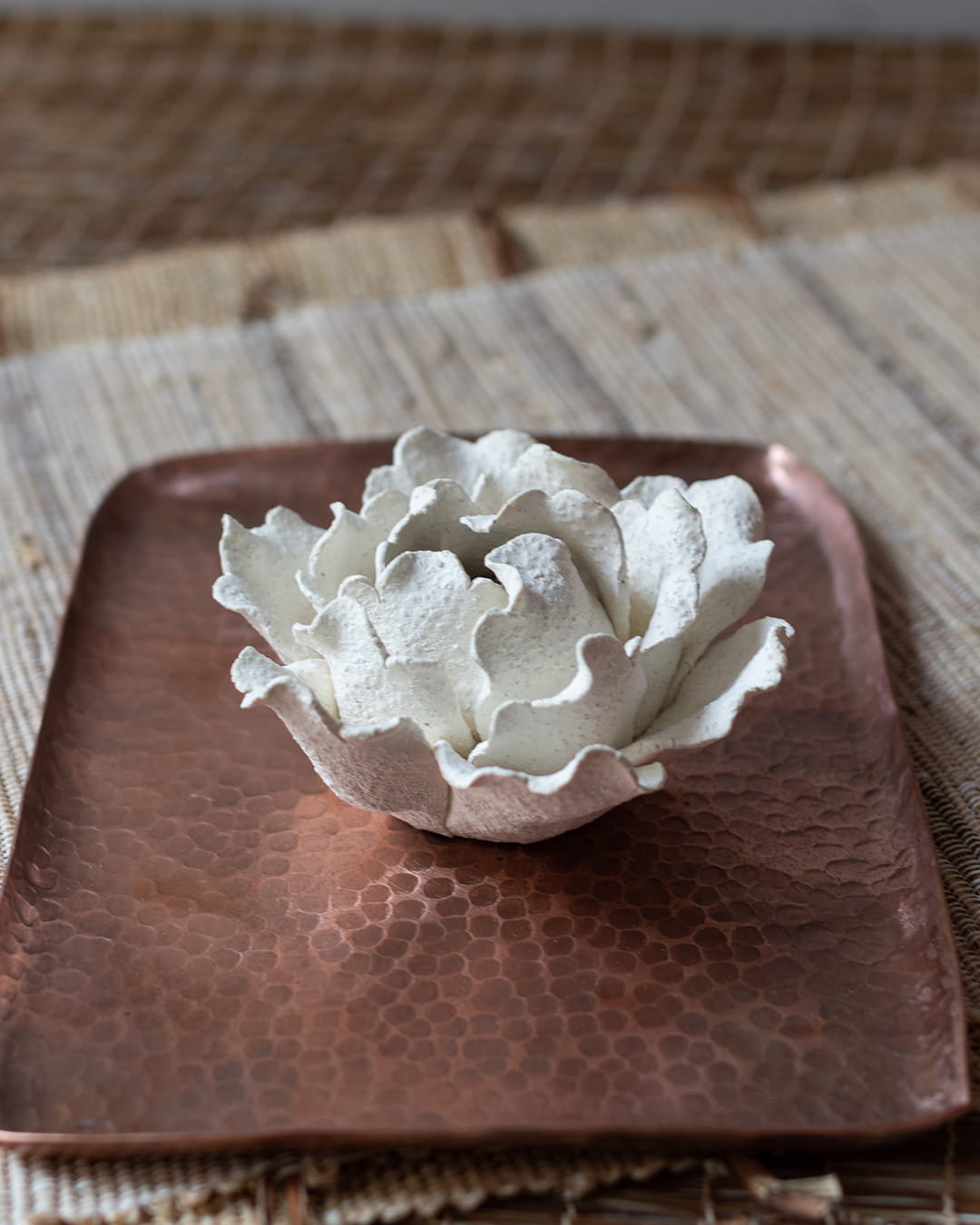 White ceramic incense holder on a copper tray.
