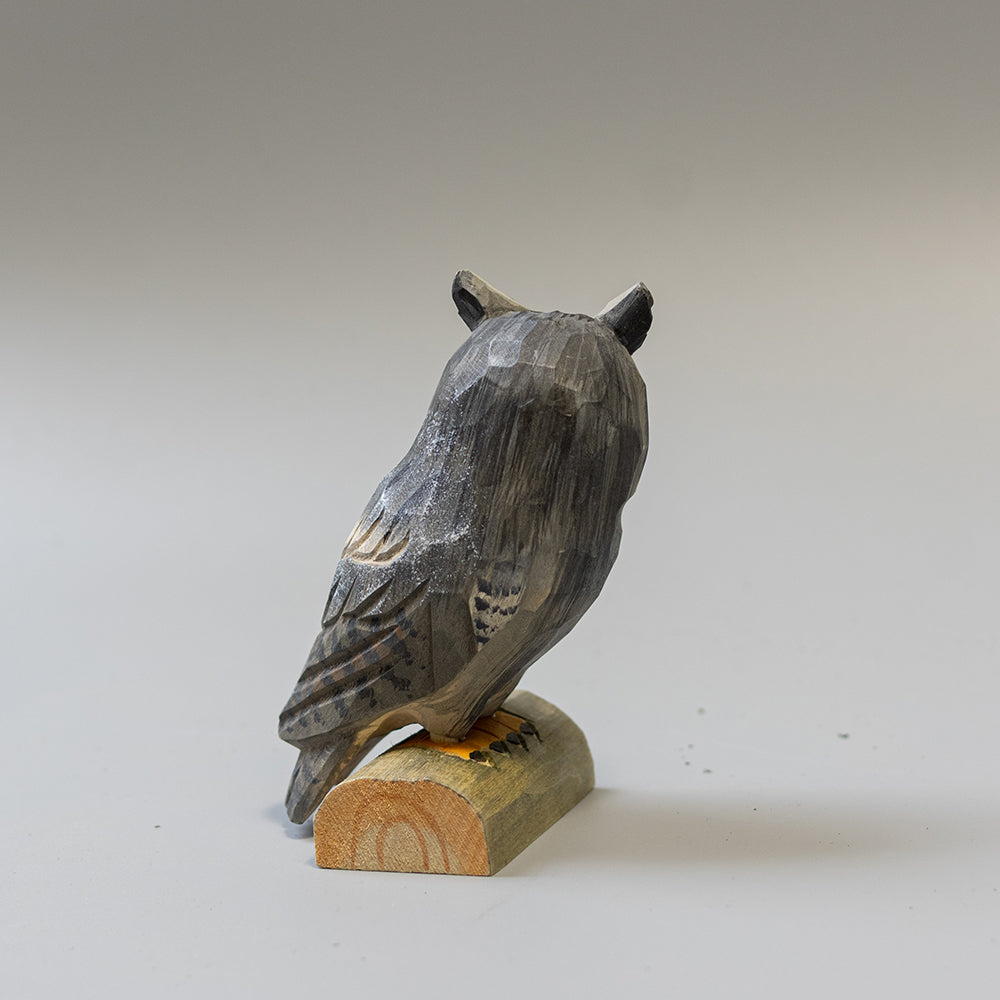 Hand carved wooden Great Horned Owl figurine showing feather tufts and mottled plumage, on a wood base. 