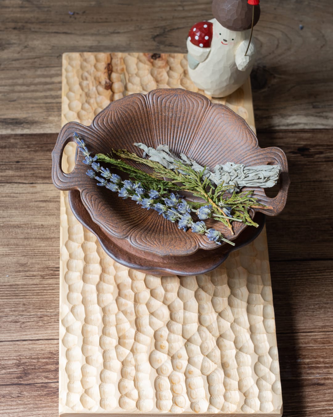 A rustic, two-piece ceramic aromatic warmer made from dark Aged Ore Clay, with a lotus-leaf-shaped dish resting on the stove base.