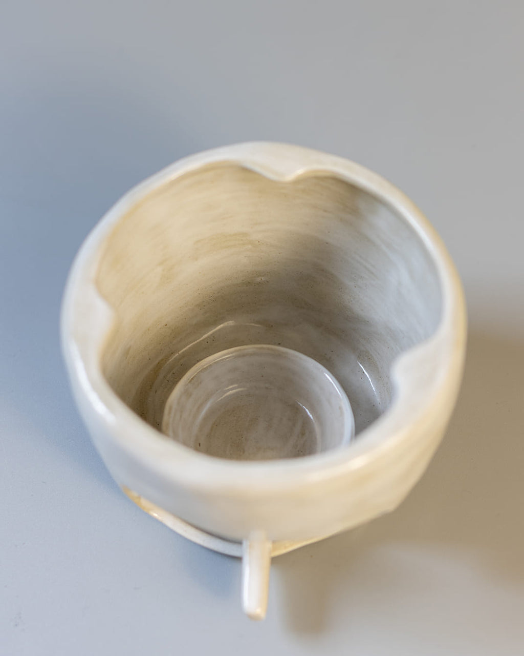 A cute, cat-shaped ceramic fragrance warmer with a white Kohiki finish, resting on its stove base with a lit tealight visible inside.