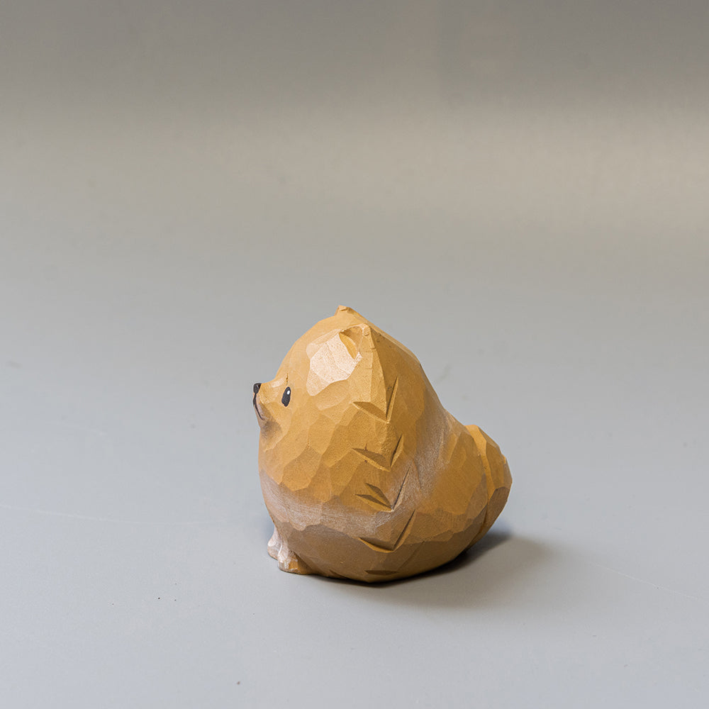 Wooden sculpture of a Pomeranian on a plain background