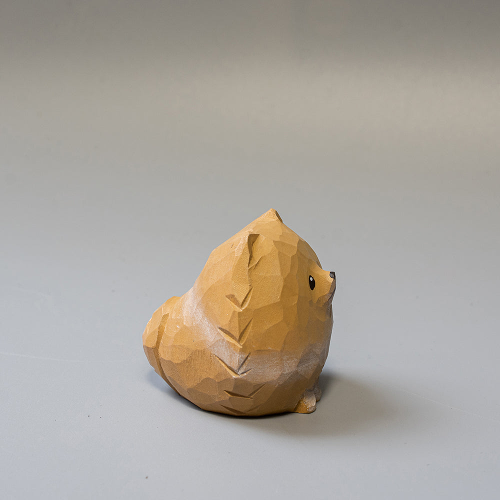 Wooden sculpture of a Pomeranian on a plain background