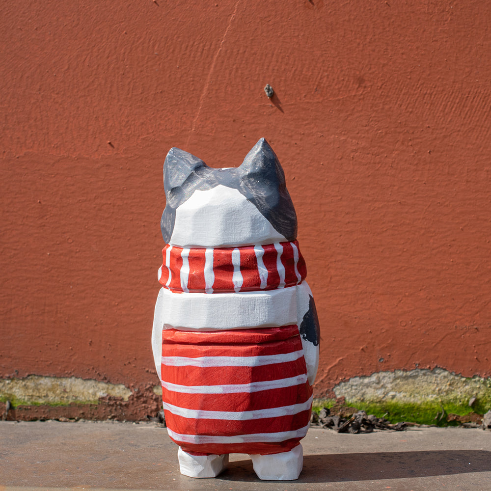 Hand-carved wooden cat figurine with a red-and-white striped scarf. Christmas-themed wood figurine, detailed wood carving, high-quality wooden figurines.