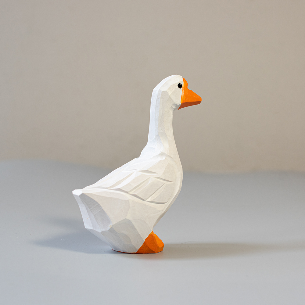 Wooden goose figurine with orange feet and beak on a light gray background