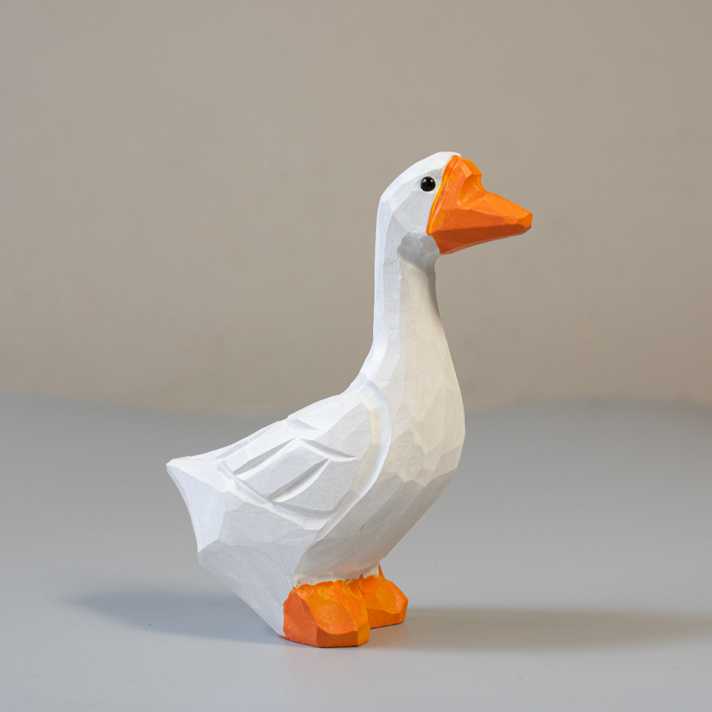 Wooden goose figurine with orange feet and beak on a light gray background