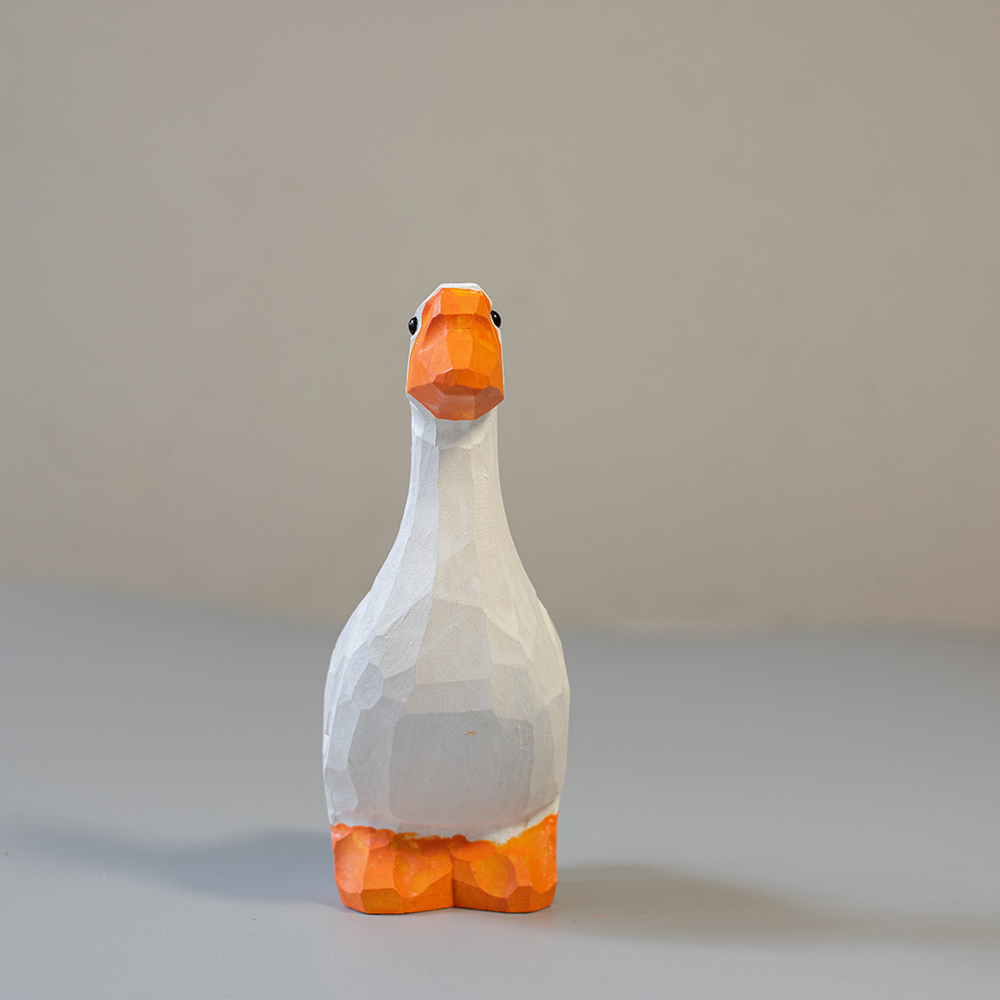 Wooden goose figurine with orange feet and beak on a light gray background