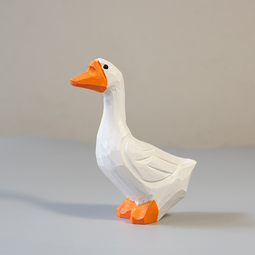 Wooden goose figurine with orange feet and beak on a light gray background