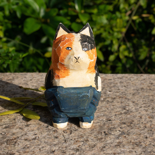 Hand-carved wooden figurine of a lounging calico cat in overalls, a playful addition to cat lover decor.