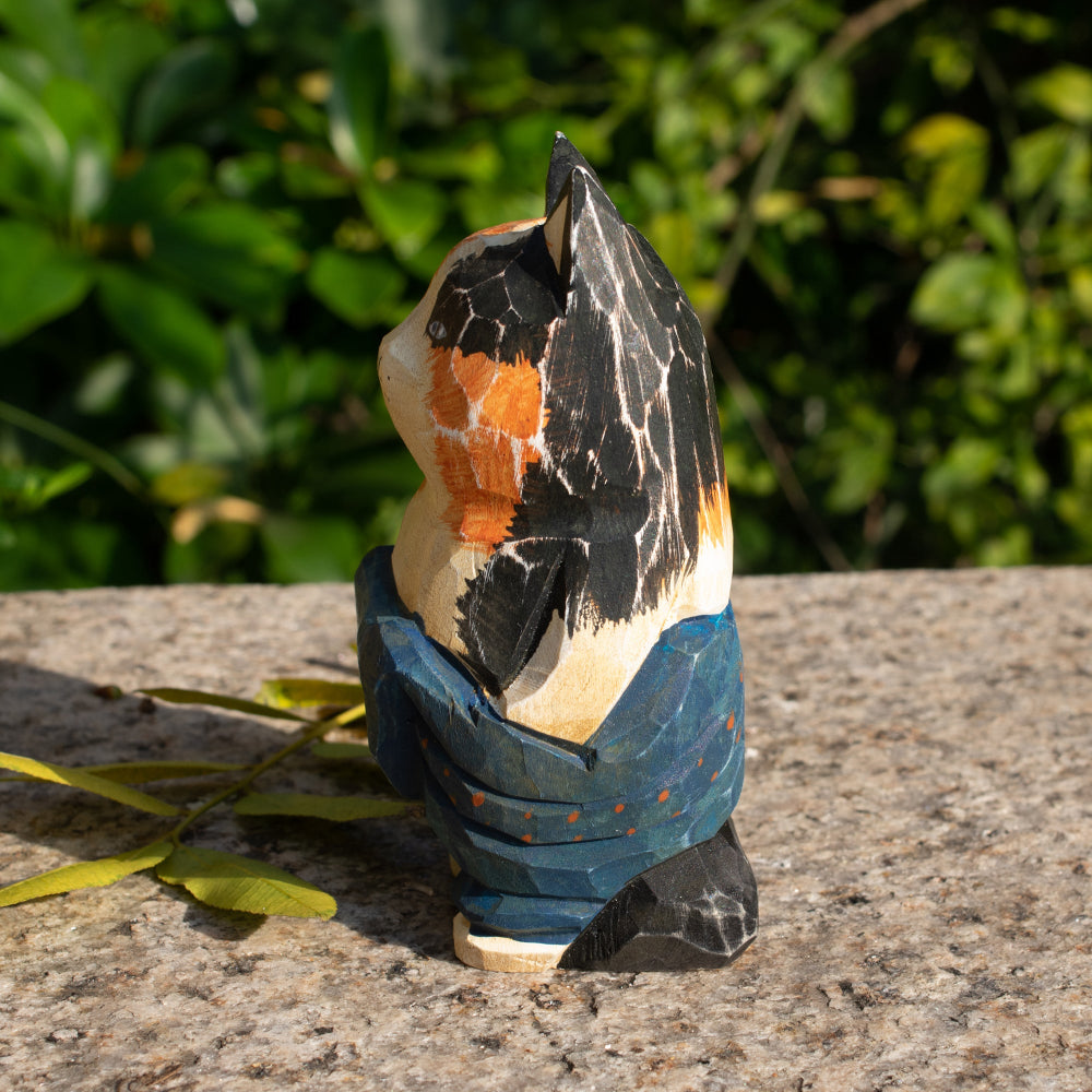 Hand-carved wooden figurine of a lounging calico cat in overalls, a playful addition to cat lover decor.