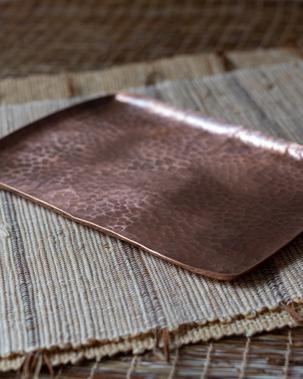 A rectangular, hand-hammered solid copper tray with a textured Tsuchime surface, laid on a linen mat.
