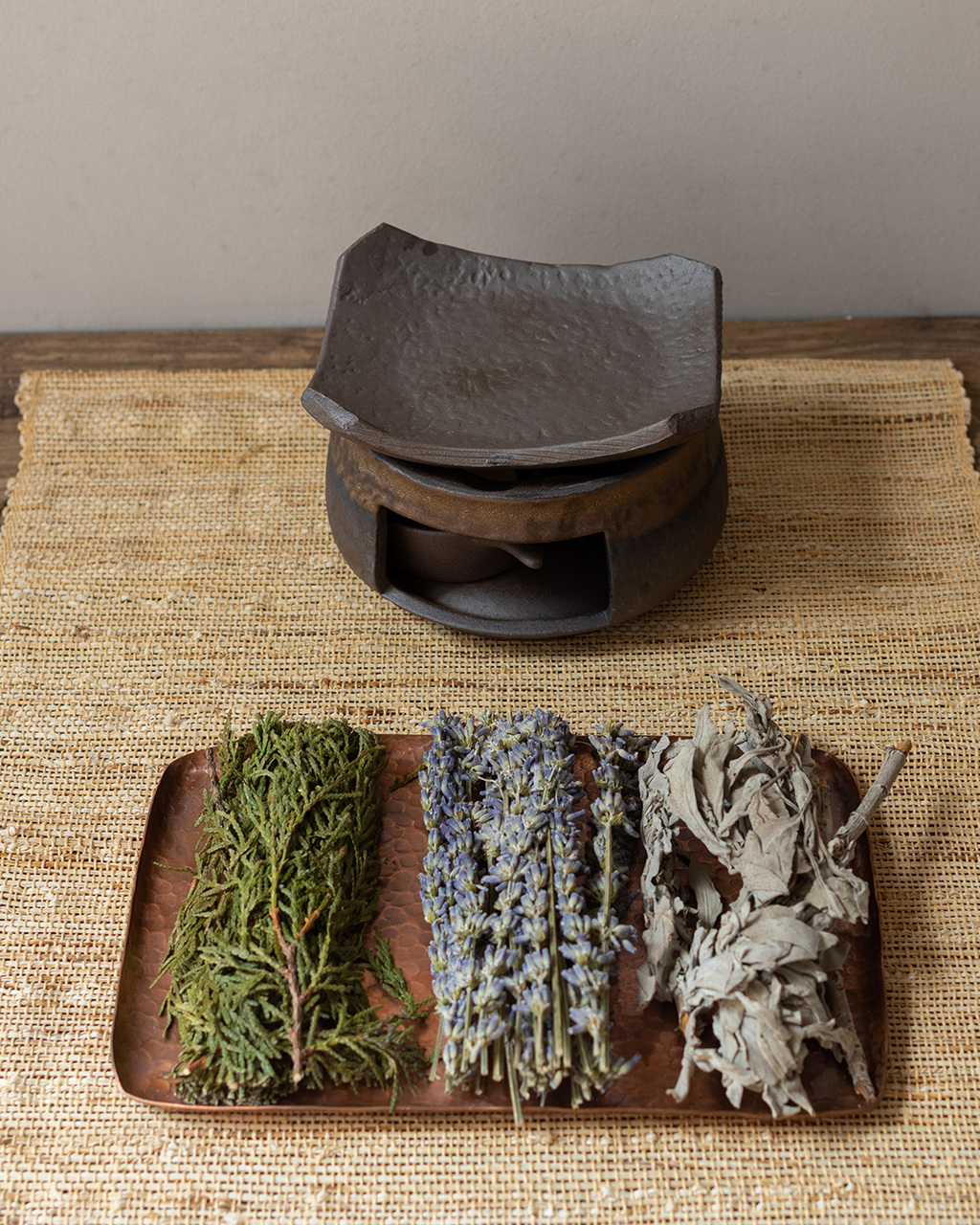 Dried herbs on a solid copper tray, with an aroma warmer.