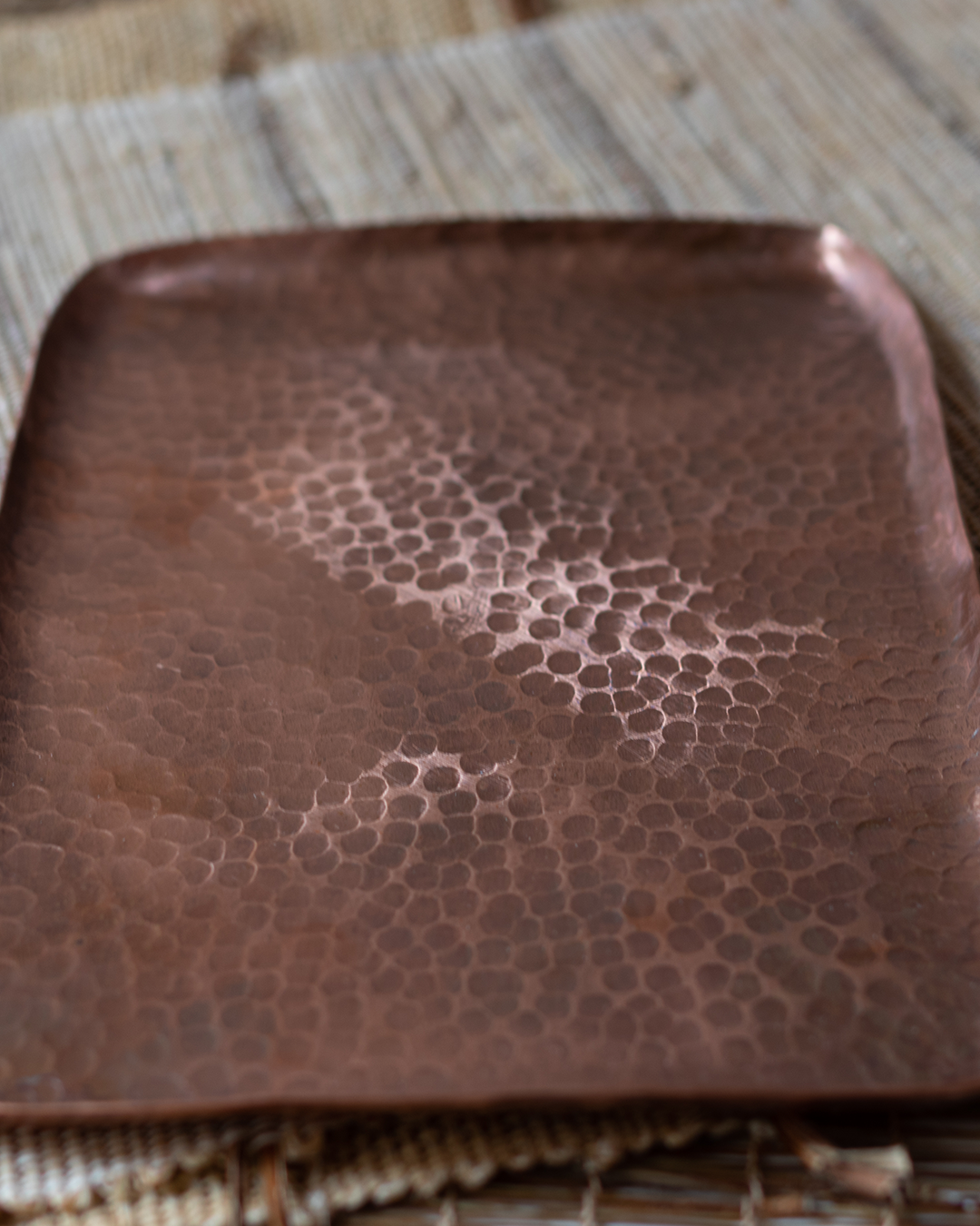 A rectangular, hand-hammered solid copper tray with a textured Tsuchime surface on a linen mat.
