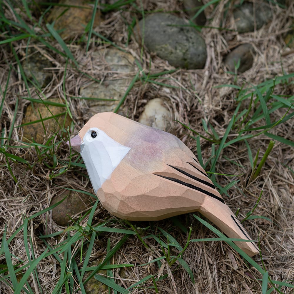 Wooden Vinous-throated Parrotbill figurine on grass and stones