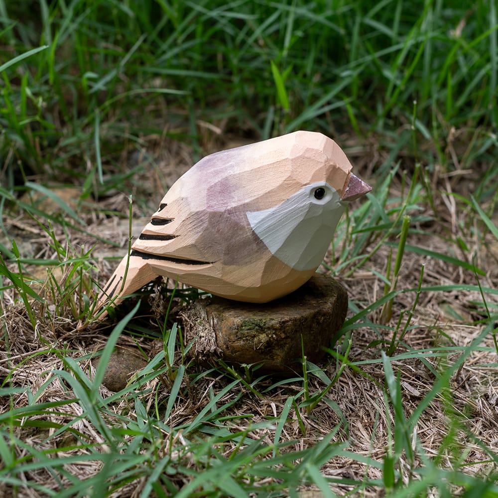 Wooden Vinous-throated Parrotbill figurine on grass and stones