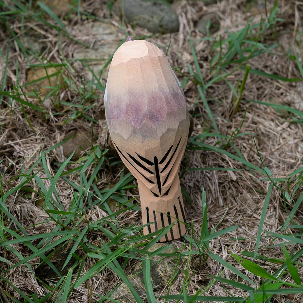 Wooden Vinous-throated Parrotbill figurine on grass and stones
