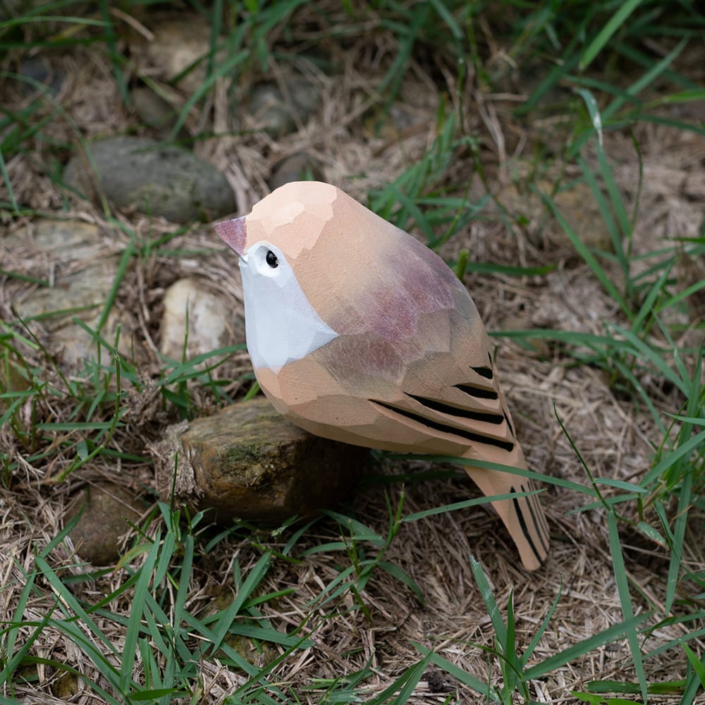 Wooden Vinous-throated Parrotbill figurine on grass and stones