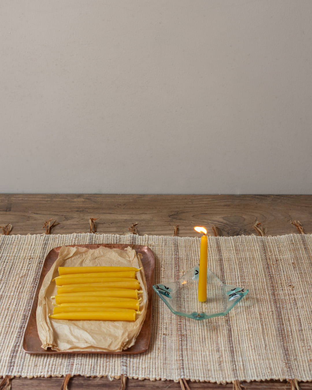 A set of nine small, thin beeswax ritual candles (chime candles) laid out on brown paper.