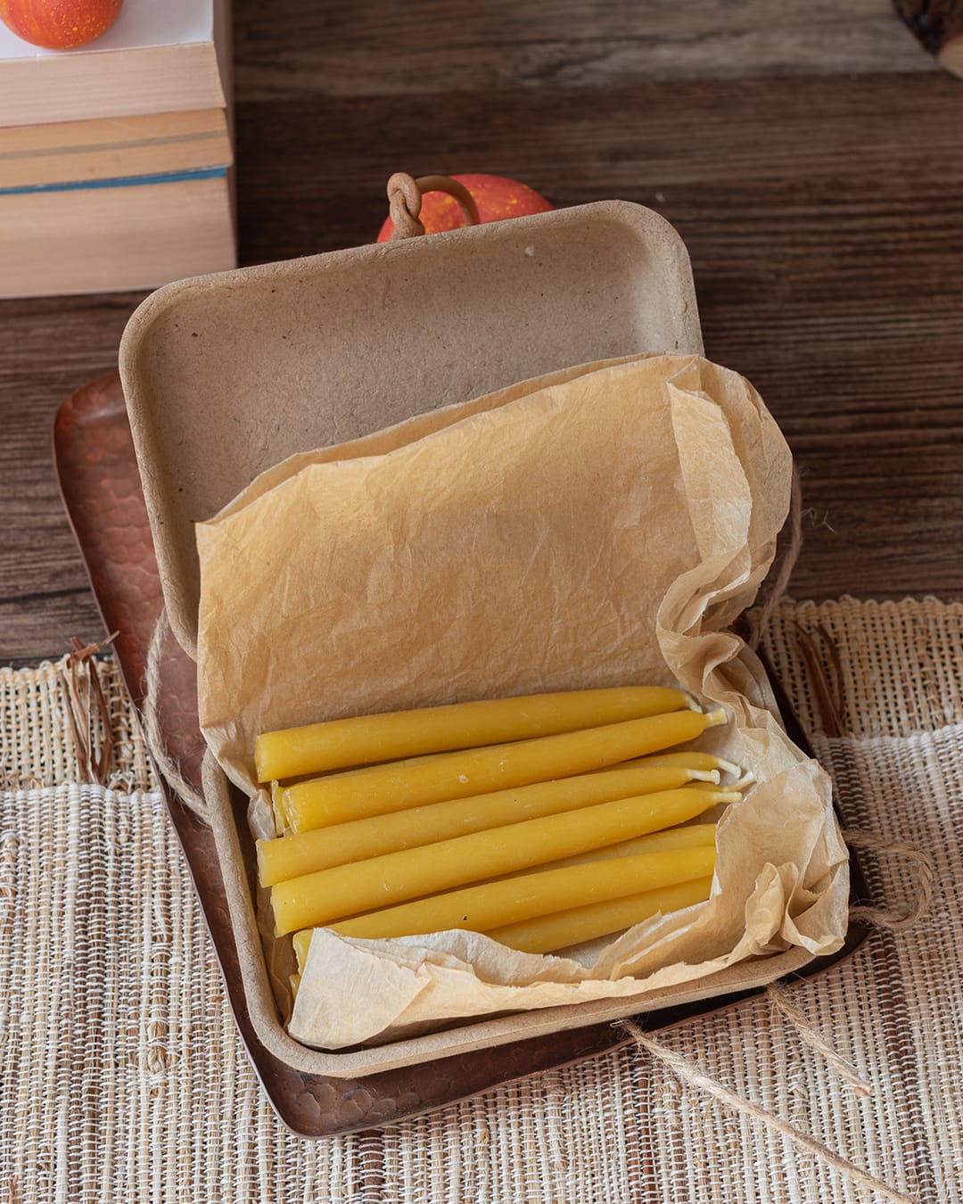 A set of ten small, thin beeswax ritual candles (chime candles) laid out on brown paper.
