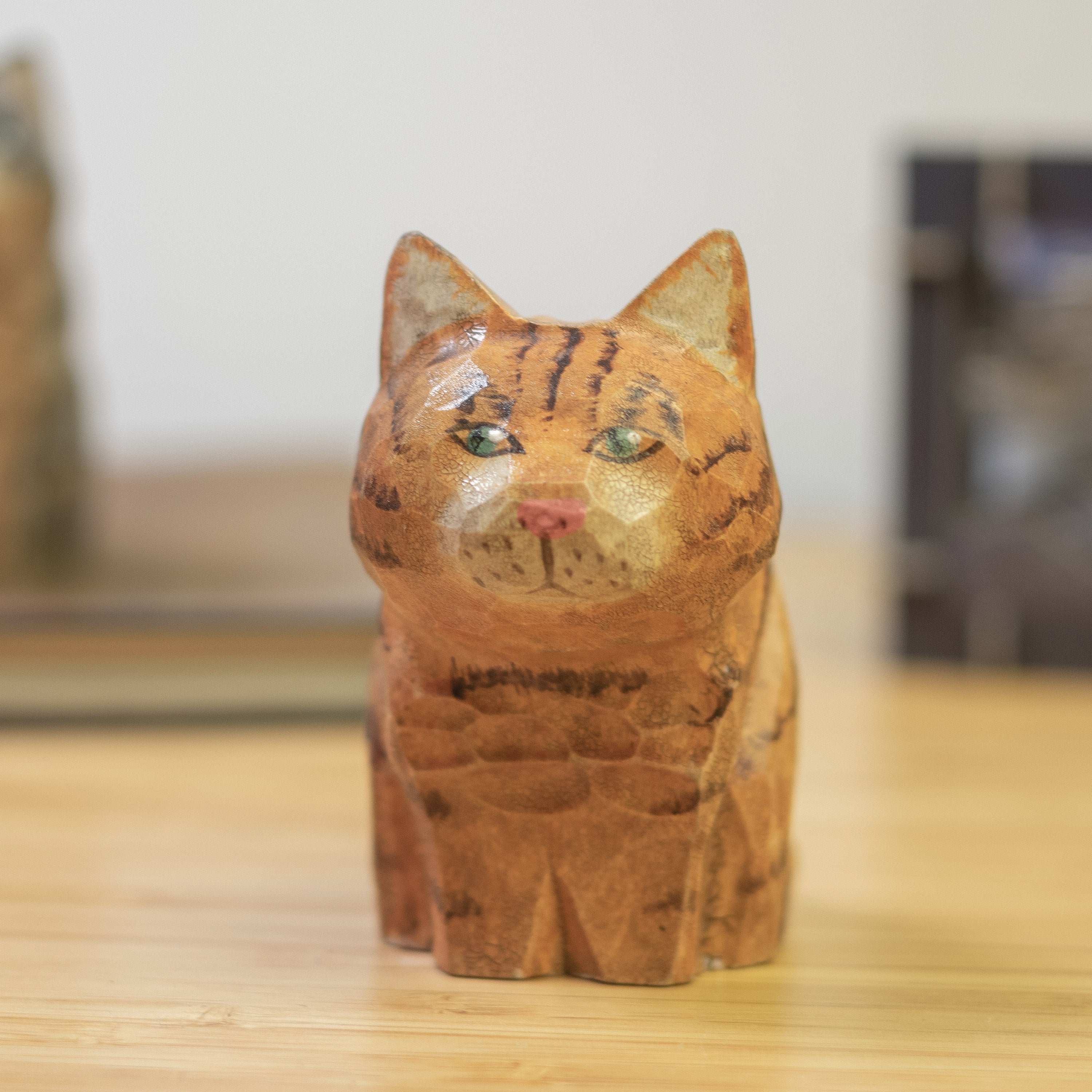 A hand-carved wooden figurine of an orange tabby cat with a vintage aesthetic finish.