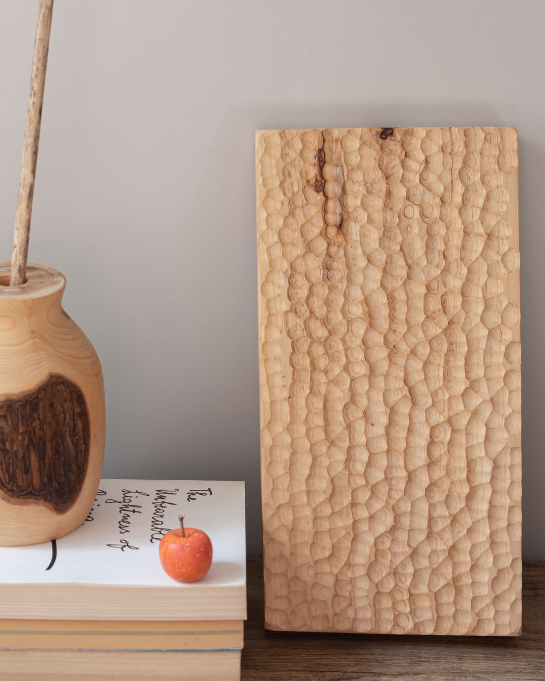 A rectangular, solid wood tray with a deep, hand-chiseled honeycomb texture, shown standing vertically on a dark wood surface.
