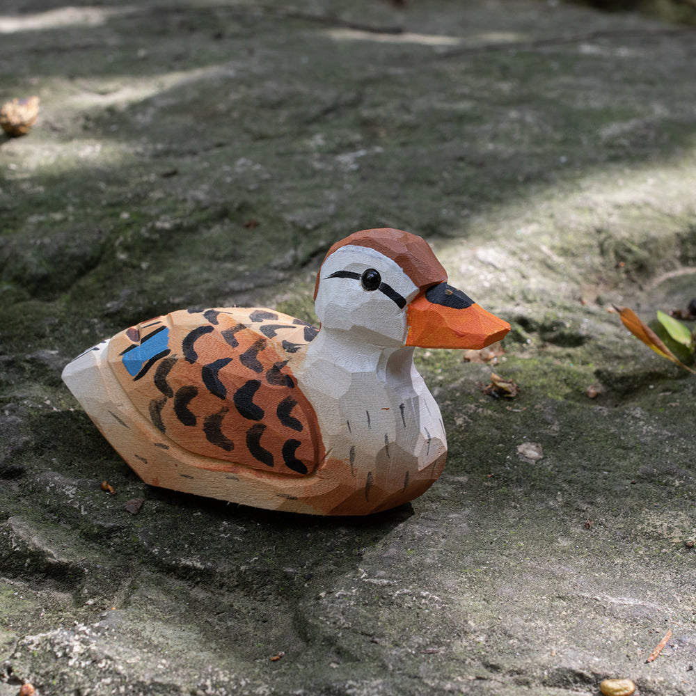 A hand-carved wooden figurines of a  spotbilled duck. 
