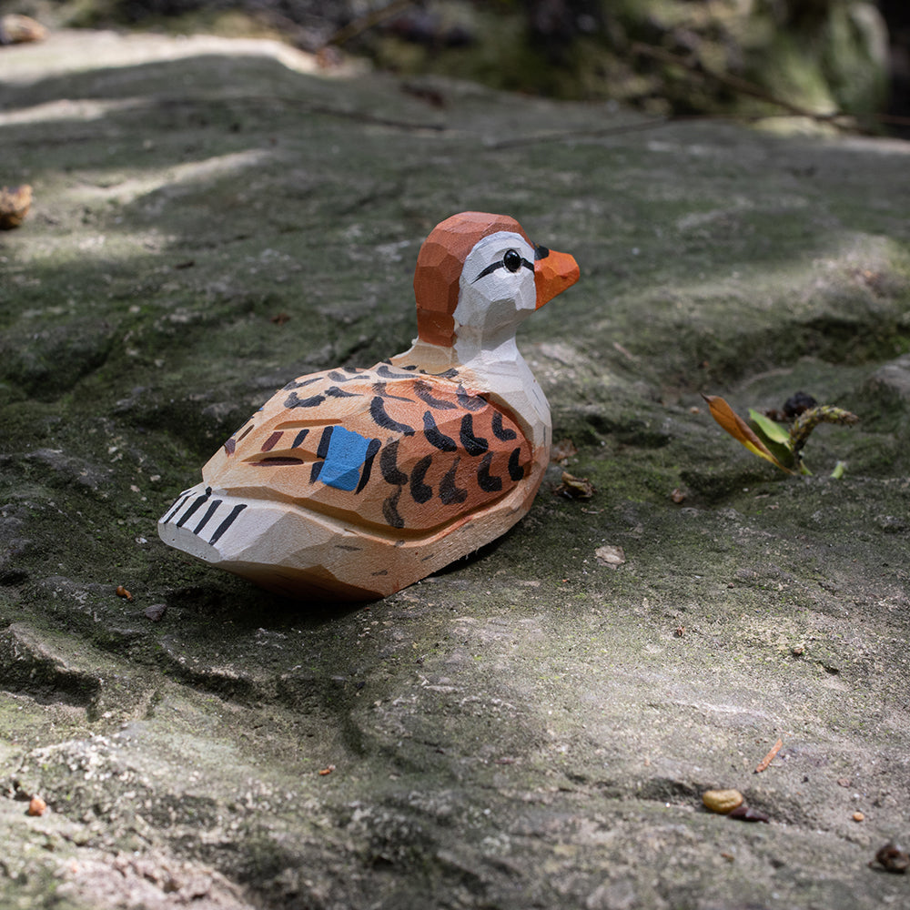 A hand-carved wooden figurines of a  spotbilled duck. 