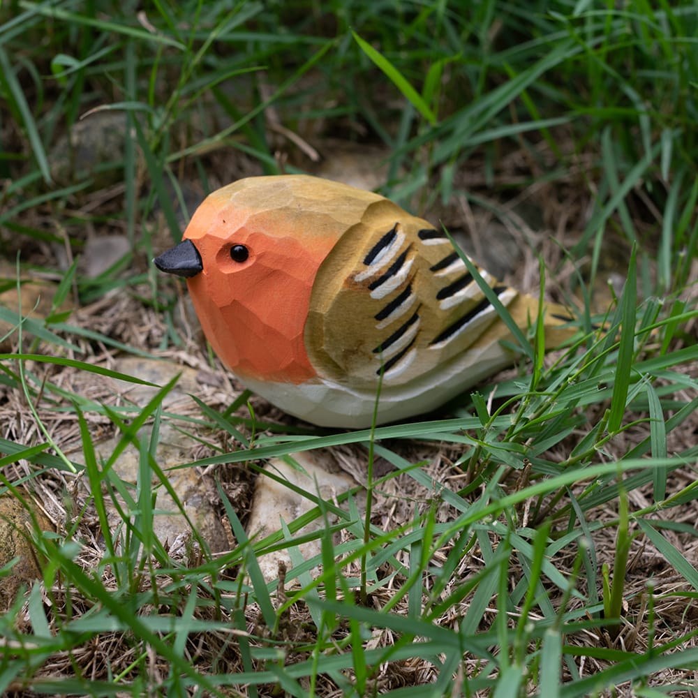 Wooden european robin figurine with colorful patterns on a grassy background
