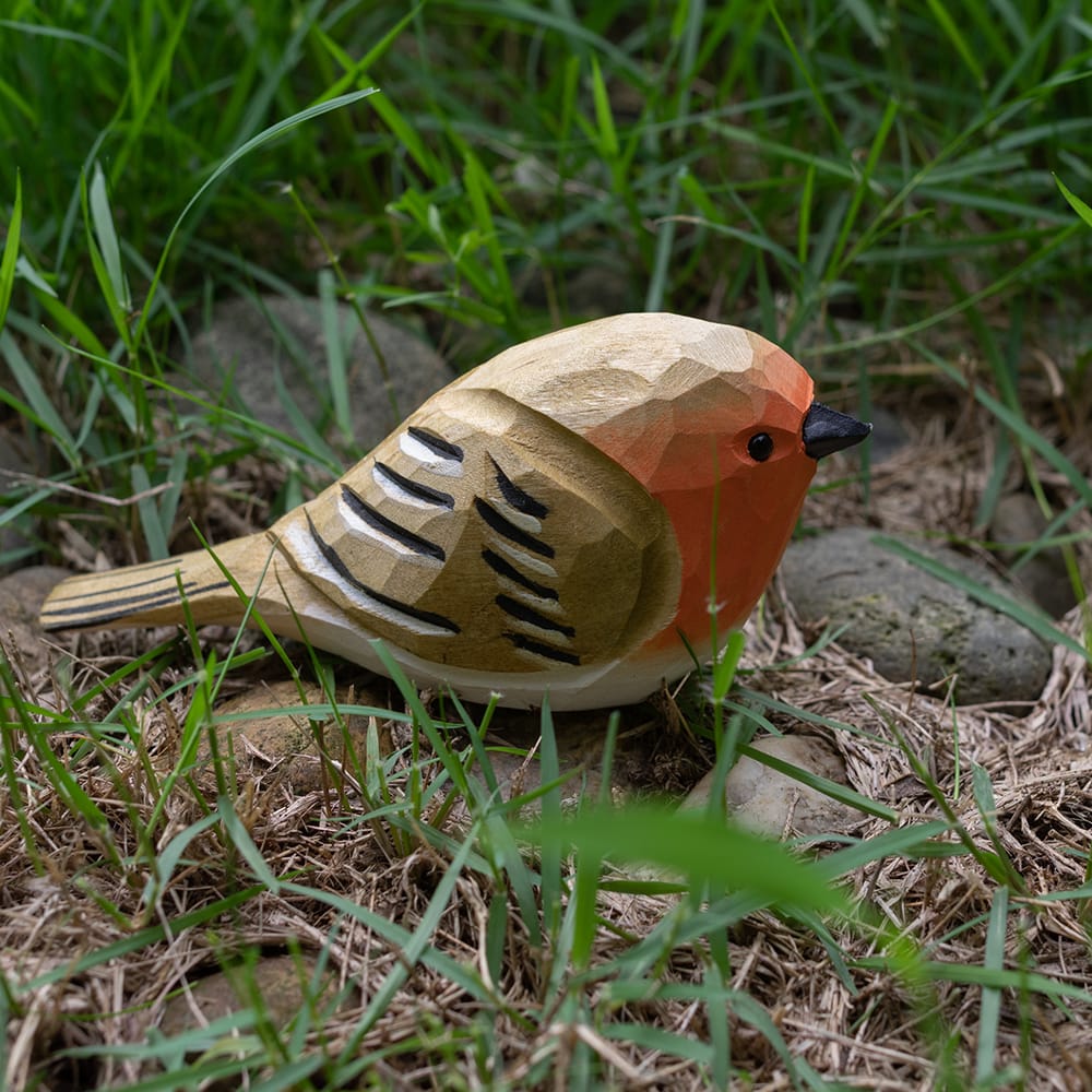 Wooden european robin figurine with colorful patterns on a grassy background