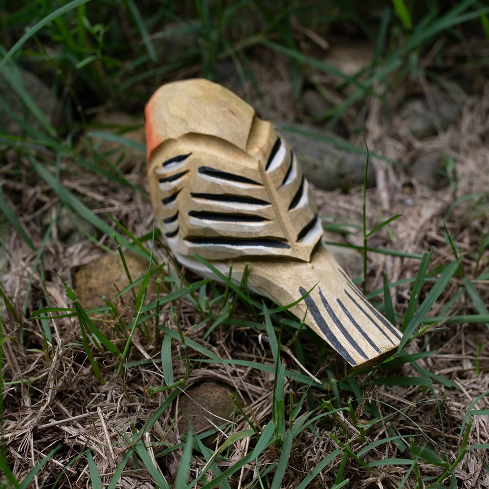 Wooden european robin figurine with colorful patterns on a grassy background