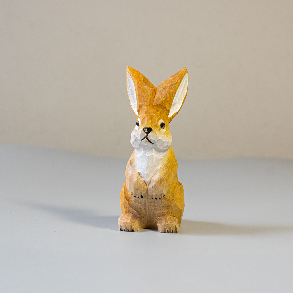 Wooden rabbit figurine on a light gray surface with a neutral background