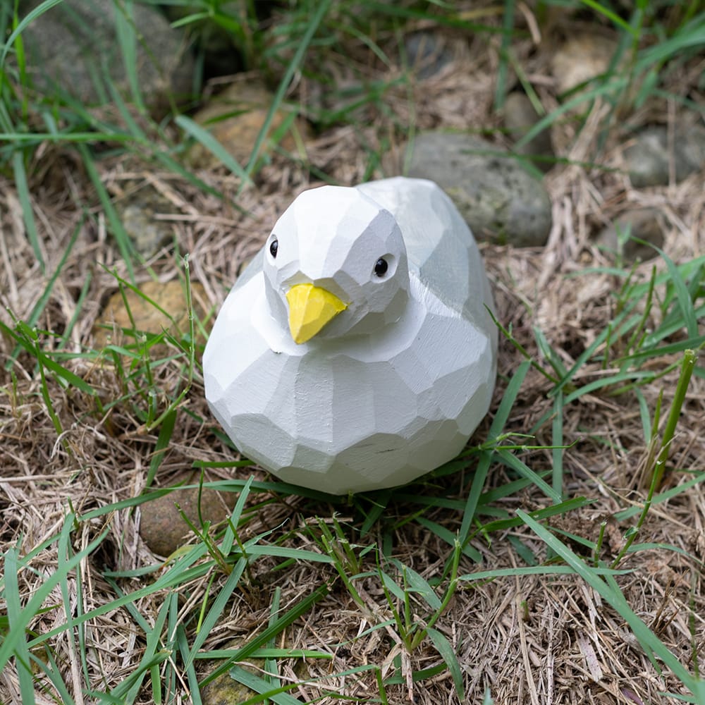 Wooden seagull figurine sitting on grass