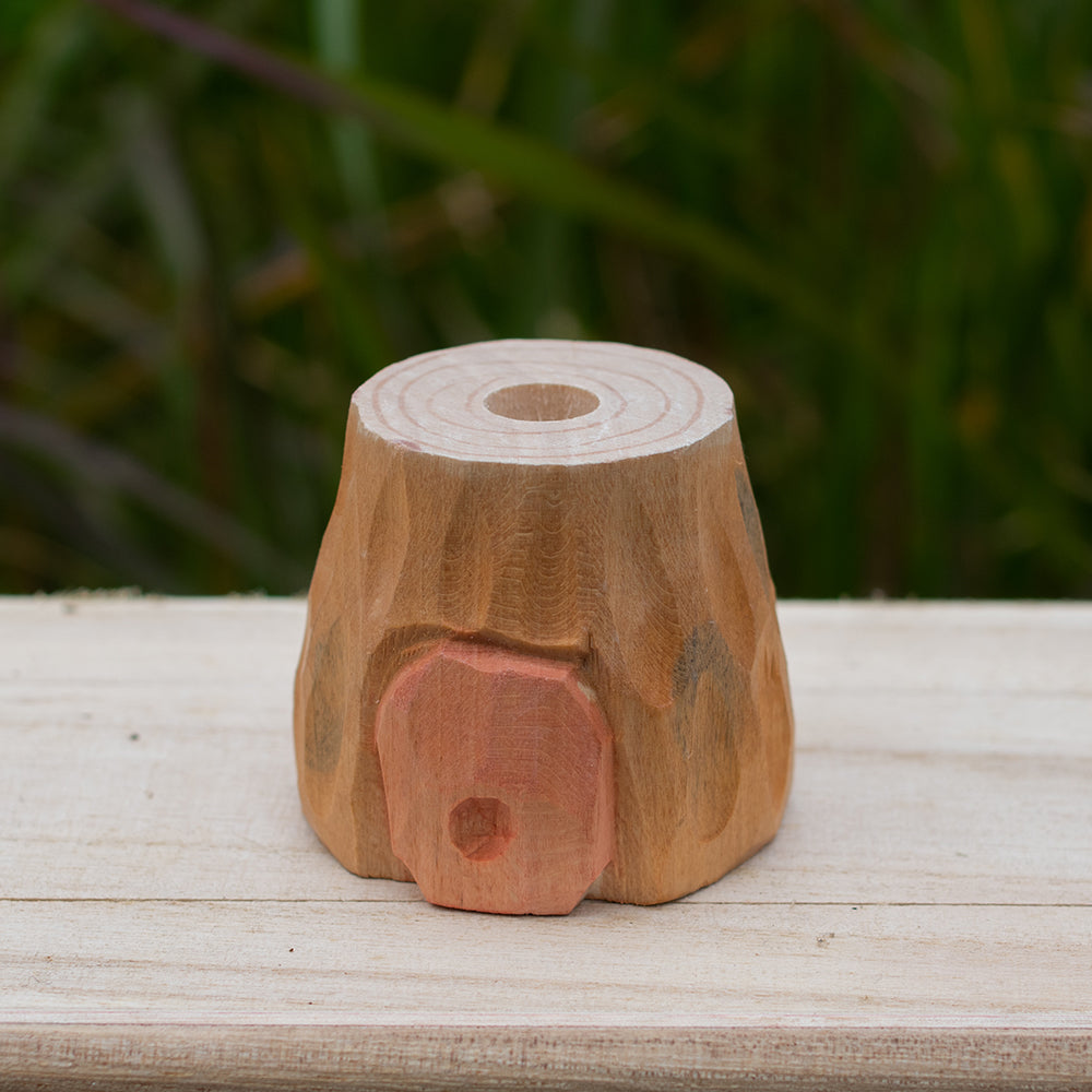 A hand-carved basswood tree stump display stand with a whimsical carved door.
